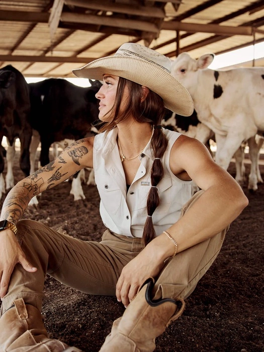Dairy farmer wearing a cowboy hat seated among cows in the barn