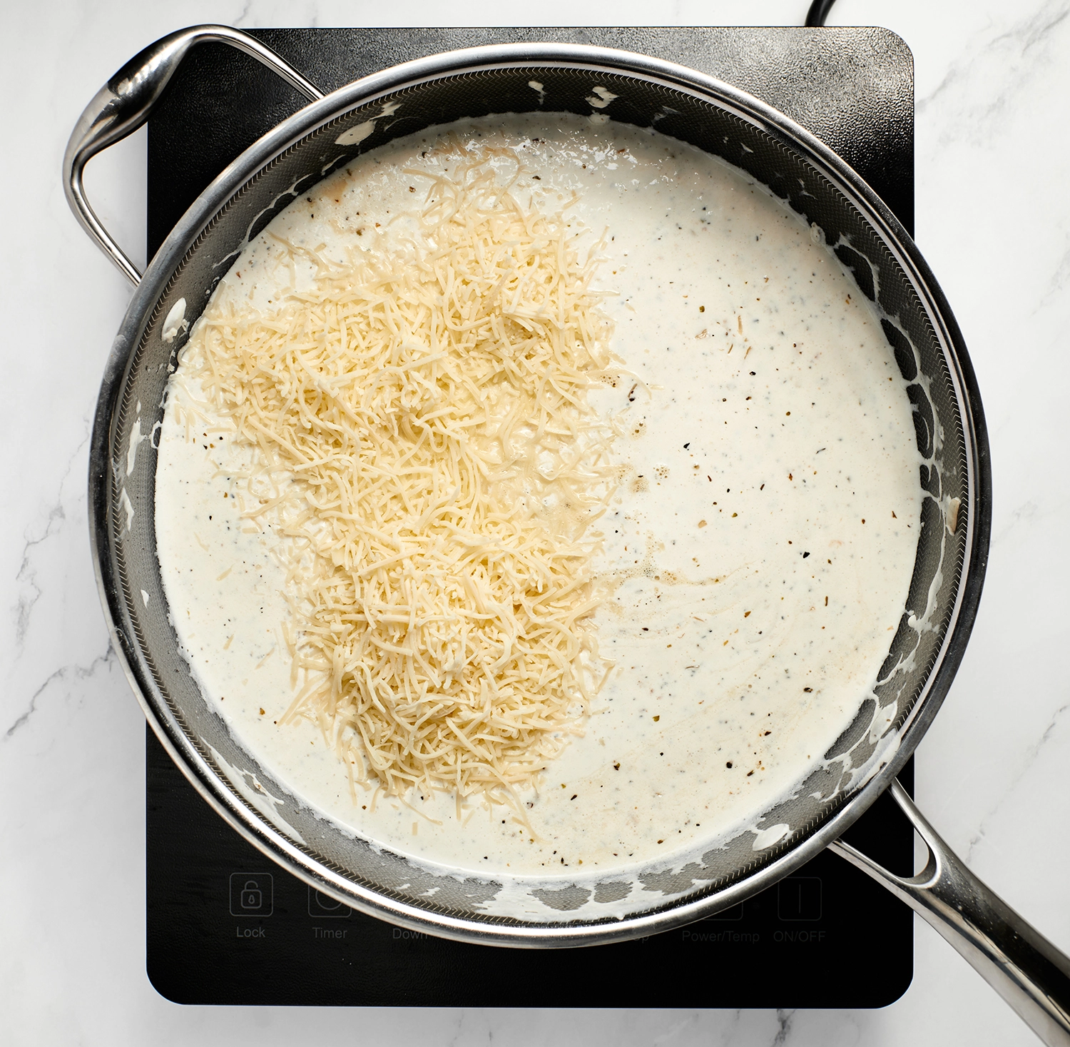Shredded Italian cheese blend stirred until the cheese melts and sauce becomes smooth and creamy in the pan.