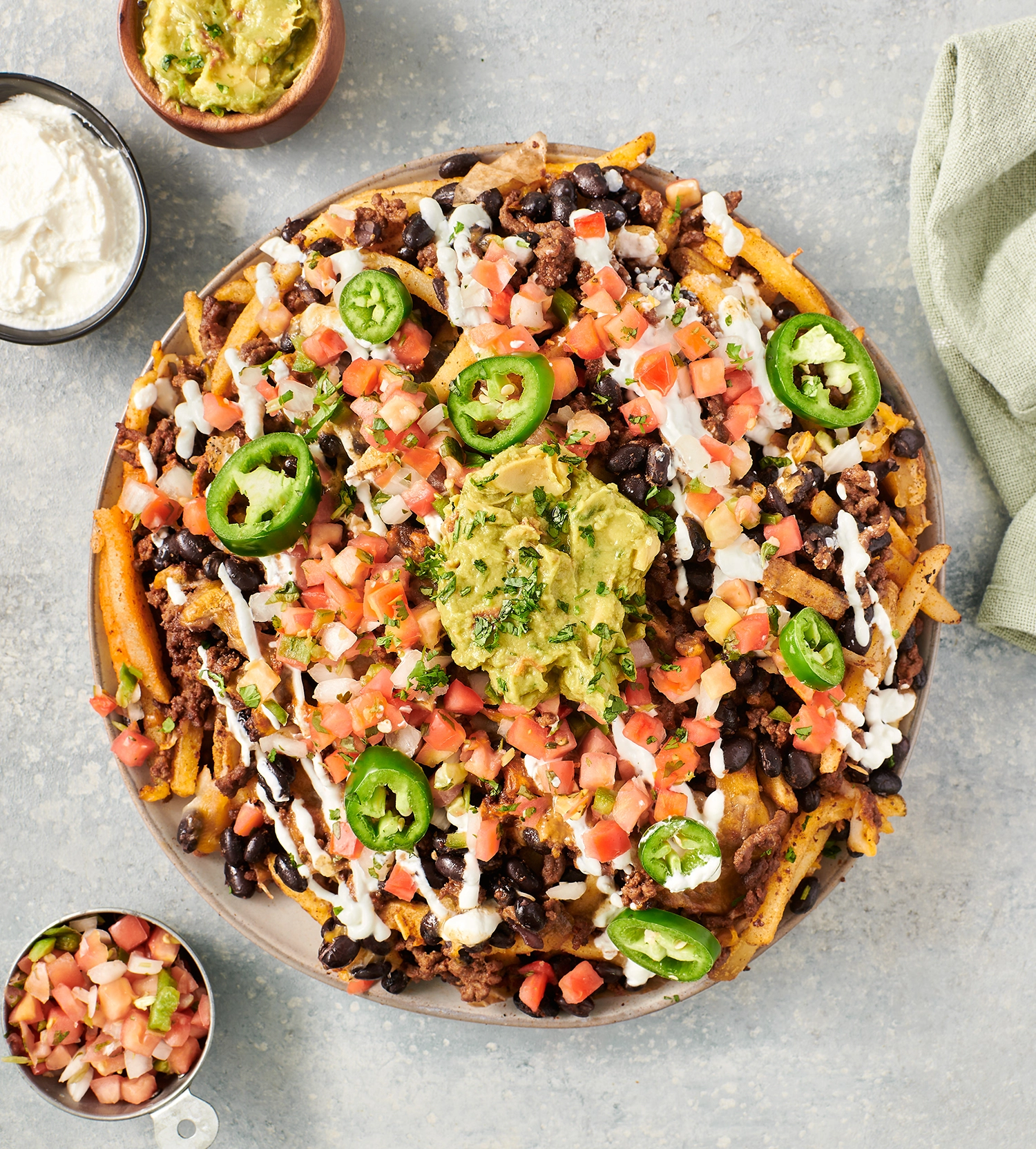 Air fryer loaded taco fries topped with pico de gallo, jalapeño peppers, and Greek yogurt ready for be served.