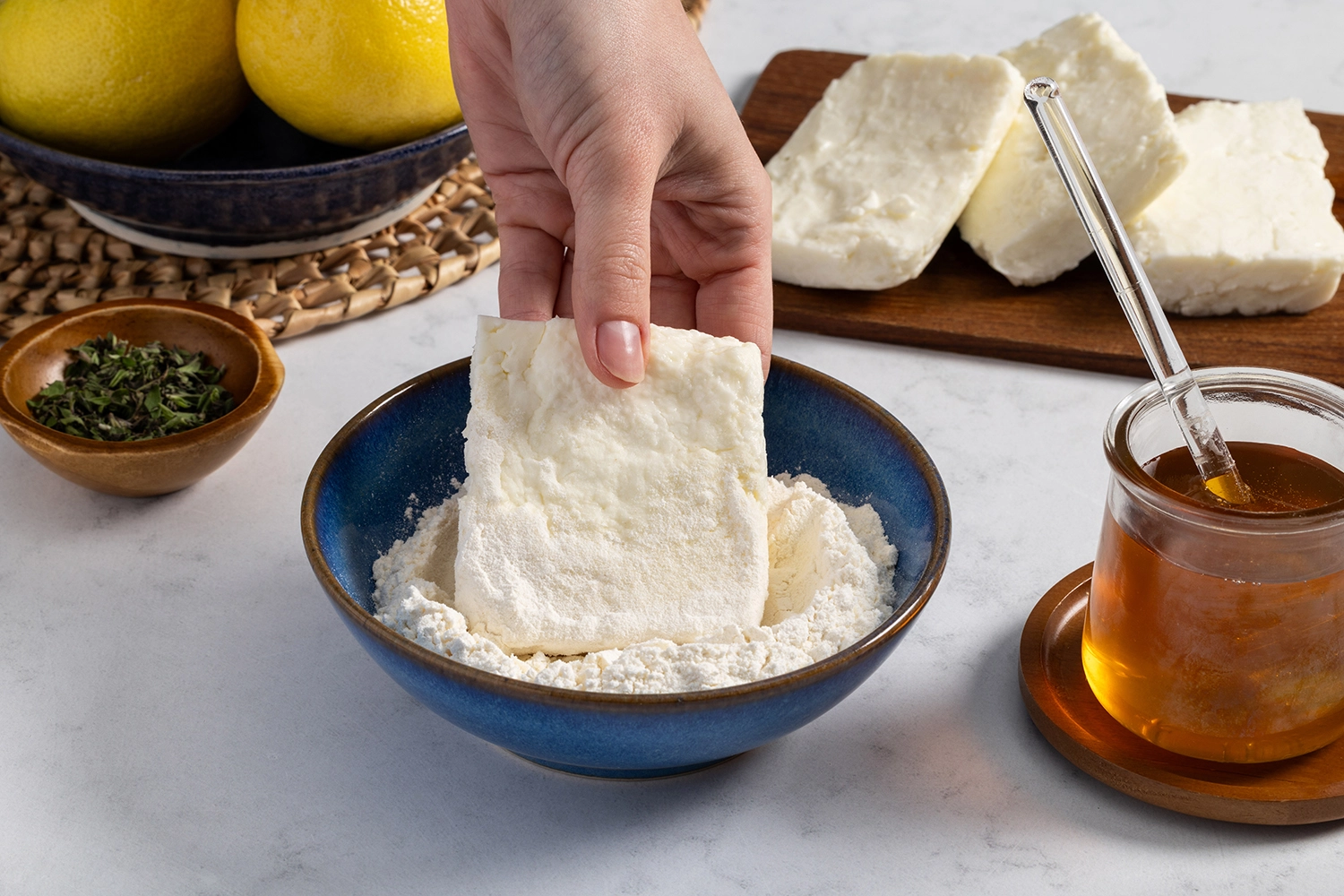 Cheese cut into 1/2 inch planks being dredged in flour.