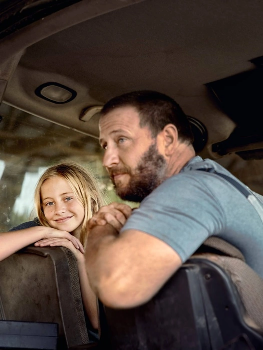 Man and young girl sitting together in a tractor cab
